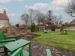 Ein Garten mit Steinmauern, einer Holzbank und einem Kiesweg.