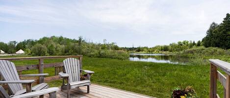 A wooden deck with Adirondack chairs and a potted plant.
