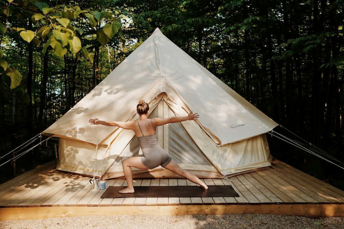A person performing a yoga pose in front of a tent.