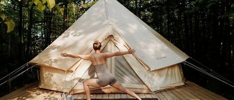 Una persona realizando una postura de yoga frente a una carpa.
