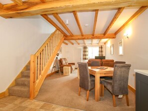 A spacious room with a wooden staircase, a dining table with chairs, and a sofa. - Bangor in Overton nr Ellesmere (Wrexham)