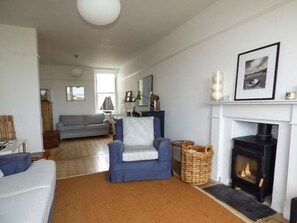 A living room with a fireplace, a sofa, a chair, and a rug. - Sandy Bank, Rhosneigr (Rhosneigr)