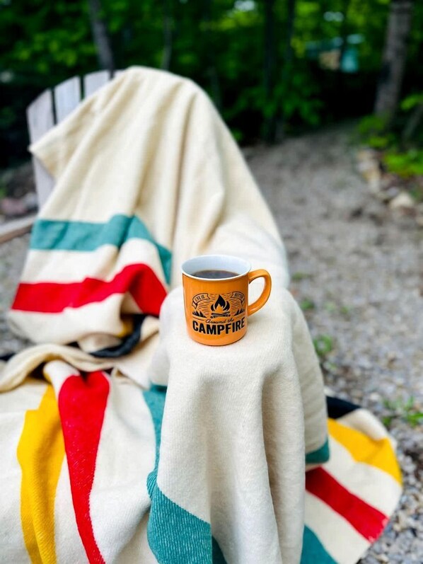 A campfire mug on a blanket with a forest background.
