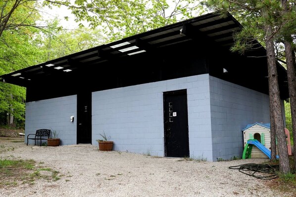 Un bâtiment avec un toit noir, une façade bleue et un petit espace de jeux équipé d’un toboggan.