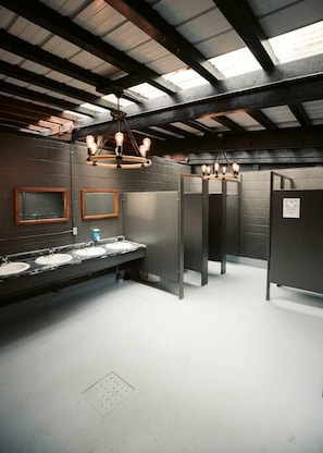 A restroom with three sinks, a mirror, and a ceiling with exposed beams.