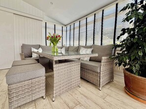 A wicker sofa set with a glass-top coffee table, a potted plant, and a window with blinds. - Topsails, Totland Bay (Freshwater)