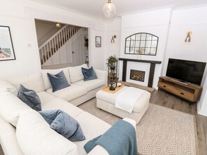 A living room with a sectional sofa, a fireplace, a television, and a staircase leading to another level. - Topsails, Totland Bay (Freshwater)