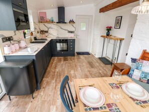 Una cocina con salpicadero de mármol, armarios negros y una mesa de comedor de madera dispuesta con platos y vasos.