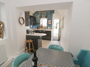 A modern kitchen with a dining area, a wooden stool, and a table with a polka dot tablecloth.