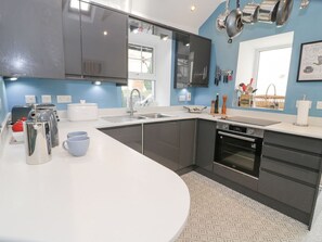 A modern kitchen with a white countertop, stainless steel appliances, and a window providing natural light.