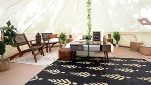 Uma tenda com mesa, cadeiras e plantas em vasos.