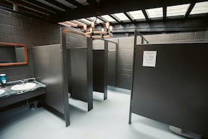 Baño con dos lavamanos, un espejo y una lámpara en el techo.