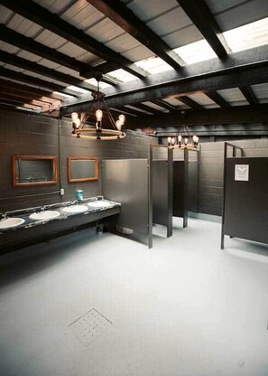 A public restroom with multiple sinks, mirrors, and a row of stalls.