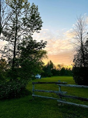 Une clôture en bois rustique, un champ verdoyant et un petit bâtiment blanc, le tout situé dans un cadre rural.