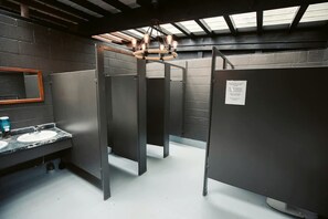 Des toilettes équipées de deux lavabos, d’un miroir et d’un luminaire au plafond.