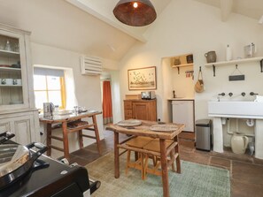 A kitchen with a wooden table, chairs, a small refrigerator, and a sink. - Bryn Canaid, Aberdaron Gwynedd (Pwllheli)