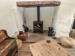 A cozy room with a wood-burning stove, a rustic wooden bench, and a woven rug. - Bryn Canaid, Aberdaron Gwynedd (Pwllheli)