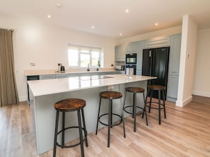 A modern kitchen with a large island, bar stools, and built-in appliances. - Linden View, Combe Martin (Ilfracombe)