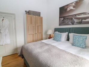 A bedroom with a bed, a wardrobe, a painting, and a lamp.