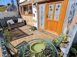 A patio with a green metal table, a small round table, and potted plants. - The Museum, Nenthead, Cumbria. (Alston)