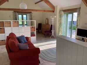 Una sala de estar con un sofá rojo, armarios blancos, un televisor y vistas al exterior.