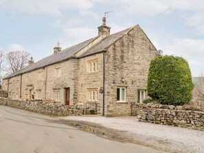A stone building with multiple windows, a chimney, and a well-maintained hedge. - Eastburn Cottage, Newbiggin (Leyburn)