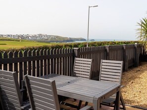 Un patio con una mesa y sillas, una farola y vistas a la costa.