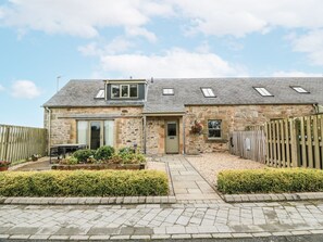 A stone house with a sloped roof, a front door, and a small porch area. - Thorneydyke Cottage, Stirling (Stirling)