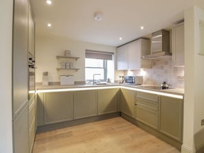 A modern kitchen with light wood flooring, built-in cabinets, and a window. - Thorneydyke Cottage, Stirling (Stirling)