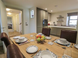 A dining area with a table set for four, a fruit bowl, and a kitchen in the background. - Thorneydyke Cottage, Stirling (Stirling)