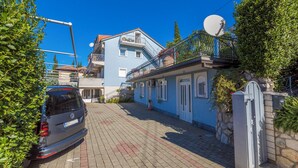 En bostadsbyggnad med en blå fasad, en satellitparabol och en parkerad bil.