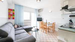 Ett modernt kök med en matplats, en grå soffa och ett färgstarkt konstverk på väggen.
