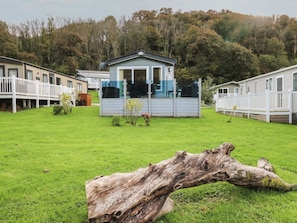 Um camping com casas móveis, um tronco grande em primeiro plano e uma colina arborizada ao fundo.