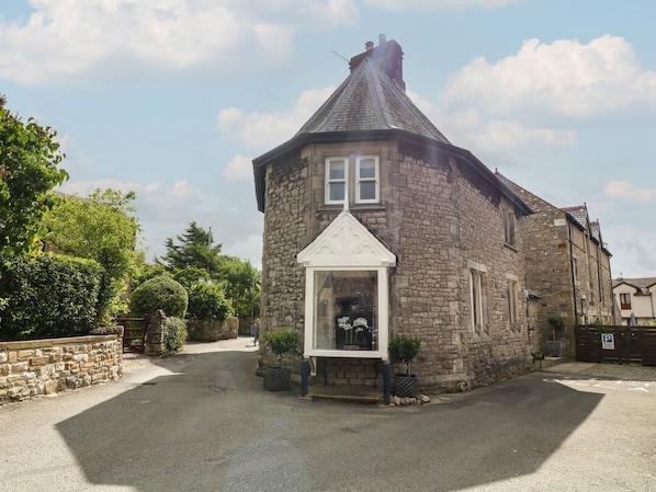 A stone building with a gabled roof, a small porch, and a window with a white frame.