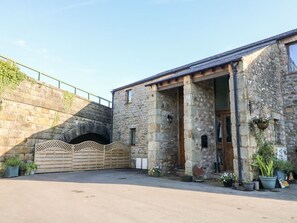Un bâtiment en pierre avec une porte en bois, un porche et une allée pavée.