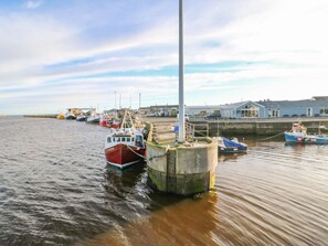 Ein Hafen mit vertäuten Booten, einer Anlegestelle und einem Gebäude im Hintergrund.
