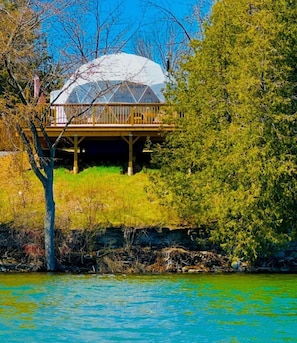 A house with a large dome roof, wooden deck, and a view of a lake.