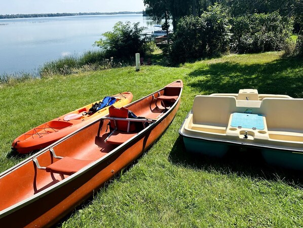 Two canoes on a grassy lakeside.