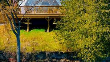 Une maison dotée d’un grand toit en forme de dôme, d’une terrasse en bois et offrant une vue sur un lac.