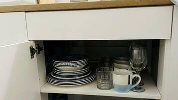 Uma cozinha com micro-ondas, cafeteira e diversos pratos e utensílios.