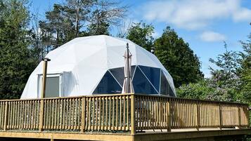 A dome-shaped structure with a wooden deck and a window.