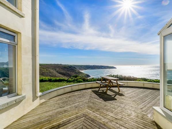 A wooden deck with a picnic table overlooking a coastal landscape.