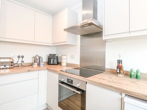 Eine moderne Küche mit weißen Schränken, einer Edelstahl-Dunstesse, einem eingebauten Backofen, einem Toaster und einer Kaffeemaschine.