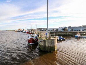 Ein Hafen mit vertäuten Booten, einer Pier und einem Gebäude mit geneigtem Dach im Hintergrund.