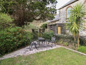 Ein Steinhaus mit Garten-Terrasse, Sitzgelegenheiten im Freien und verschiedenen Pflanzen.