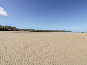Ein weiter Sandstrand mit sanften Hügeln im Hintergrund.