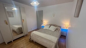 Een slaapkamer met een bed, bedlampjes, een kledingkast en een spiegel.