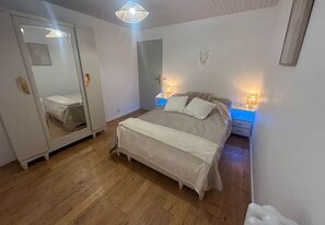 A bedroom with a bed, bedside lamps, a wardrobe, and a mirror. - Gîte* 7 pers* Quiet and natural* Near Sarlat (Vézac)