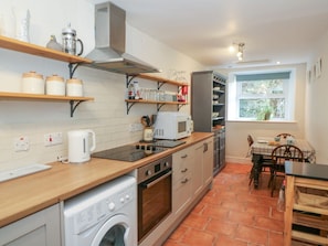 Cocina compacta con lavadora, microondas y encimera de madera.