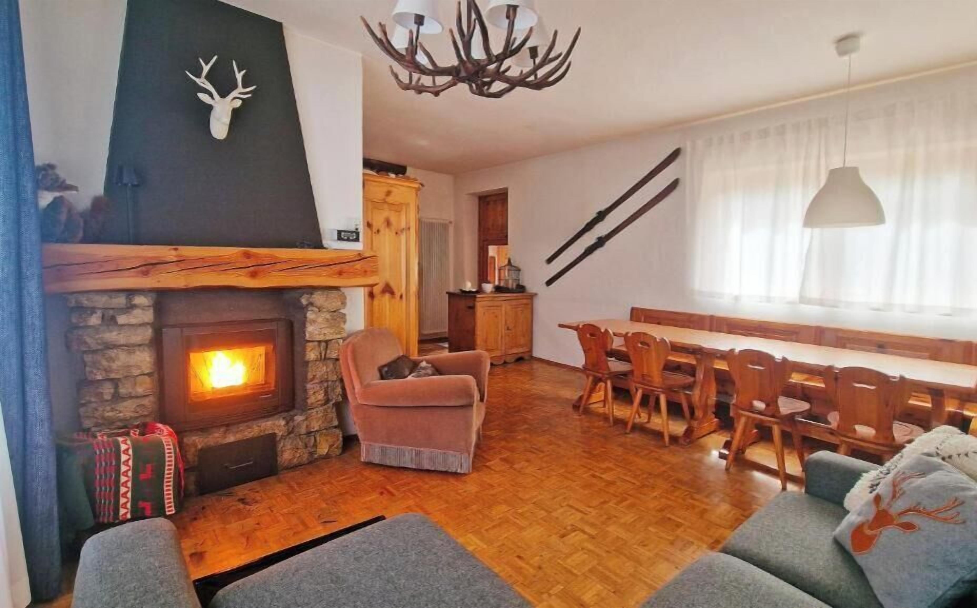 Una sala de estar acogedora con chimenea, un comedor con muebles de madera y una araña.